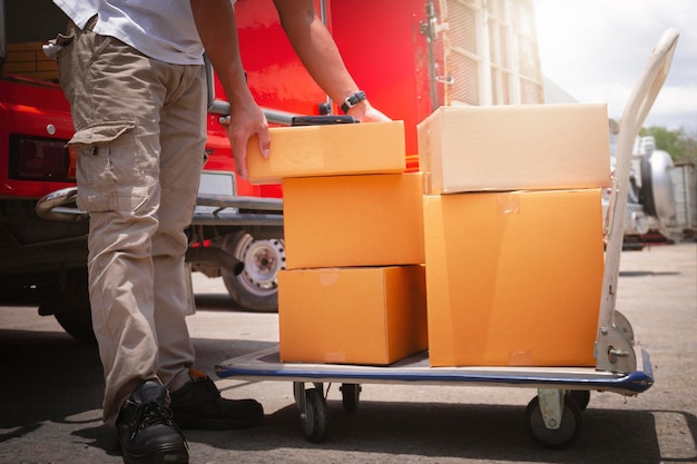 Zusteller hebt Paketkästen auf den Wagen. Arbeiter-Kurier-Lieferwagen liefern die Sendung aus