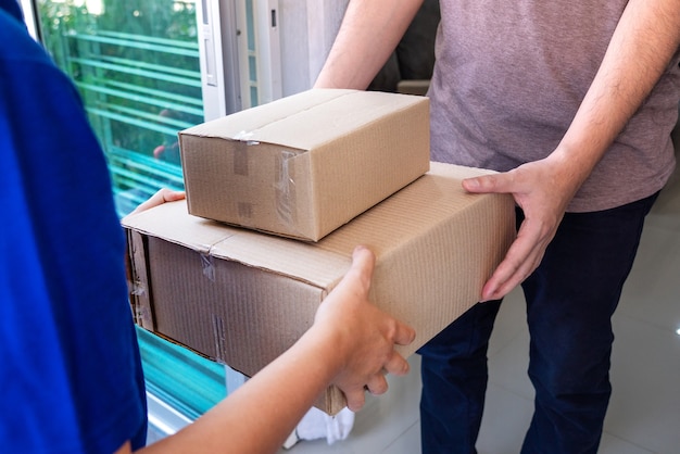 Zusteller in blauer Uniform, die Paketbox für Kunden übergibt