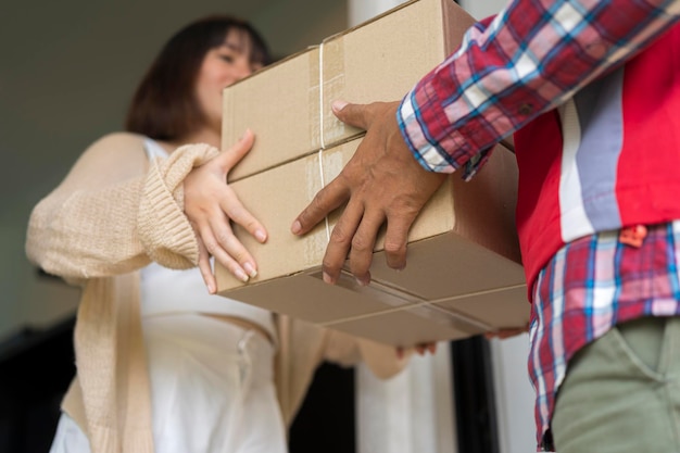 Zustellpostmann, der dem jungen Besitzer des Empfängers eine Paketbox gibt, die das Kartonpaket vom Postversand-Heimkurier- und Zustelldienst-Mind-Konzept annimmt