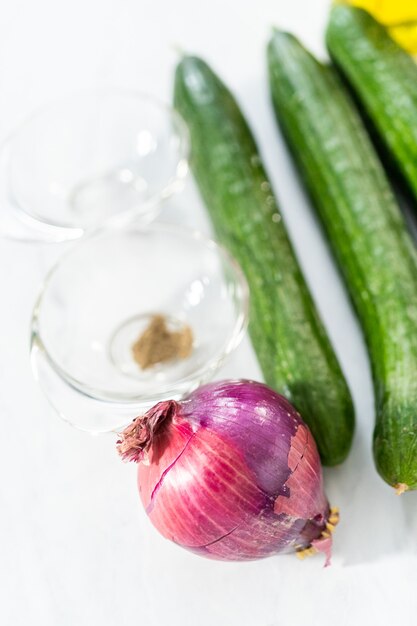 Zutat für die Zubereitung von Sommergurkensalat mit frischem Dill und lila Zwiebeln.