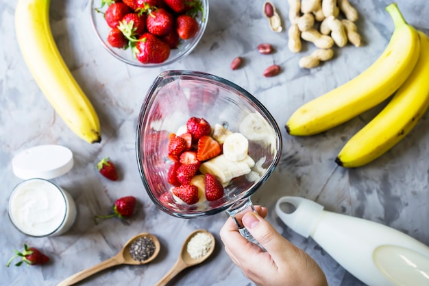 Zutaten für die Herstellung von Erdbeerbanane Smoothies auf einer grauen Tabelle