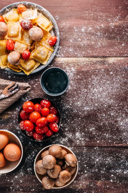 Zutaten für die Herstellung von hausgemachten Ravioli mit Pilzsauce auf einem alten Holztisch. Italienisches veganes Essen. Copyspace