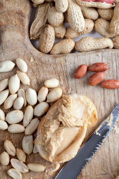 Zutaten für die Zubereitung eines schnellen Frühstücks mit Brot und Erdnüssen, Erdnusspaste geröstete Erdnüsse, köstliche Erdnussbutter und Weißbrot auf dem Tisch