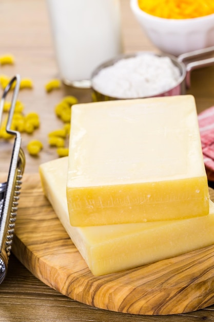 Zutaten für die Zubereitung von Makkaroni und Käse auf einem Holztisch.