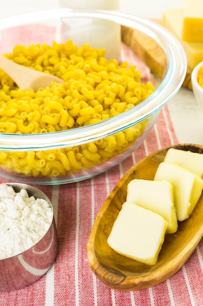 Zutaten für die Zubereitung von Makkaroni und Käse auf einem Holztisch.