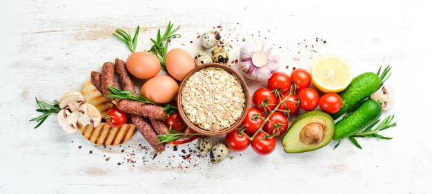 Foto zutaten für gesunde ernährung kochhintergrund eier haferwürste und frisches gemüse auf weißem holzhintergrund