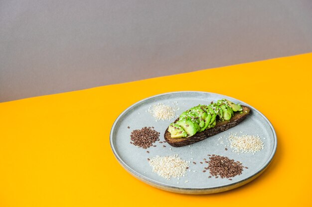 Zutaten für gesunden Avocado-Toast. Sesam Leinsamen. Vegane ketogene Ernährung. Gesundes Essen. Vegetarische trendige Guacamole. Minimalistisches Konzept im isometrischen Stil in trendigen Farben.