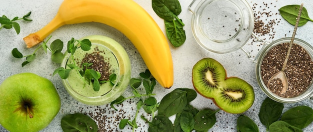 Zutaten für gesunden grünen smoothie, frischen spinat, erbsen-mikrogrün, banane, kiwi, apfel und chia-samen auf hellgrauem betonhintergrund. gesunde ernährung getränke. banner. platz kopieren.