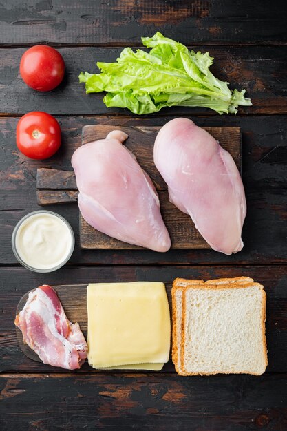 Zutaten für Sandwich, Speck, Käse, Tomaten, Hühnerfleisch, Salat, Sauce, auf alten Holztisch