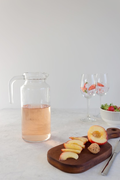 Zutaten für Sangria Erdbeerpfirsich und Roséwein und Gläser mit Eis Nahaufnahme grauer Hintergrund