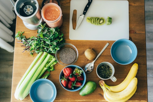 Zutaten für Smoothie-Schüssel Chia-Samen Pudding Früchte auf Holz-Tisch flach lag vegan gesund