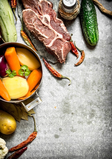 Zutaten für Suppe mit Gemüse, Gewürzen und Fleisch auf Steintisch.