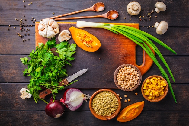 Zutaten für vegane Gemüsesuppe mit Linsen und Kichererbsen auf dunklem Holz