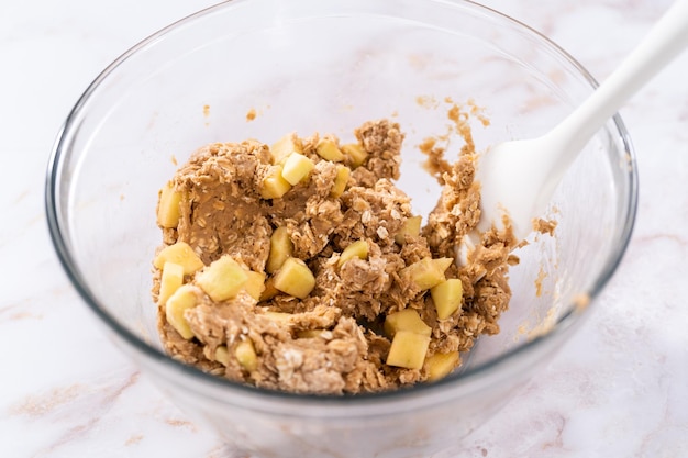 Zutaten in einer großen Rührschüssel aus Glas mischen, um Apfel-Haferkekse zu backen