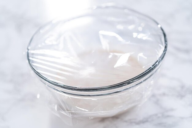 Foto zutaten in einer rührschüssel aus glas mischen, um hausgemachte briochebrötchen zu backen.