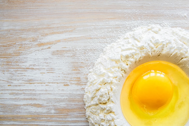 Zutaten und werkzeuge zum backen - mehl, eier und glas milch auf dem rustikalen holztisch. hausgemachte pastazubereitung