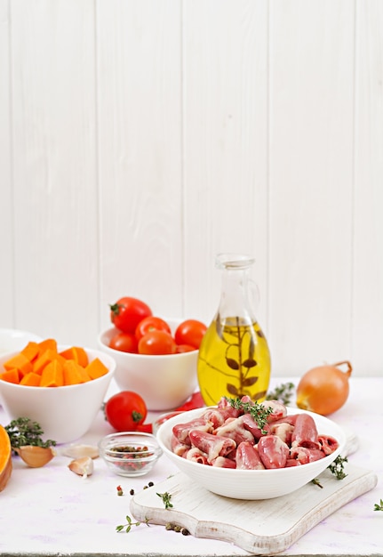 Zutaten zum kochen von hähnchenherzen mit kürbis und tomaten in tomatensauce. die beilage wird mit gekochtem reis serviert.