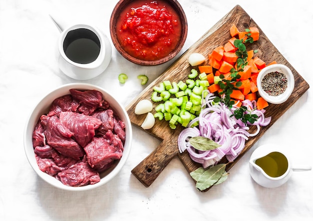 Zutaten zum Kochen von Rindfleisch in Burgunder-Rinderfilet-Tomatensauce Rotweingemüse auf hellem Hintergrund Draufsicht