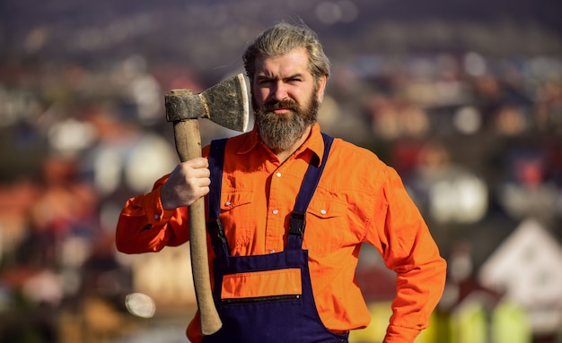 Zuversichtlich in seiner Arbeit. bauen und bauen. Fachkundiger Architekt repariert und repariert. Ingenieur Karriere. bärtiger Mann in Uniform. reifer Mann Baumeister verwenden Axt. professioneller Mechaniker, der mit Axtwerkzeug arbeitet.