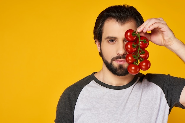 Zuversichtlich Mann hält Bündel von Tomaten vor Gesicht.