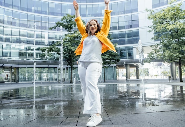 Zuversichtlich Plus Größe kurvige glückliche junge Frau tanzt Straßenbrunnen modernen Hintergrund