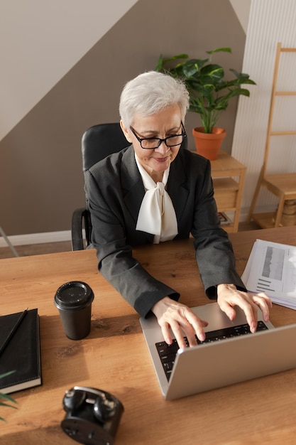 Zuversichtlich stilvolle europäische Seniorin mittleren Alters mit Laptop am Arbeitsplatz stilvolle ältere reife s