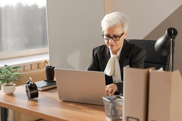Zuversichtlich stilvolle europäische Seniorin mittleren Alters mit Laptop am Arbeitsplatz stilvolle ältere reife s