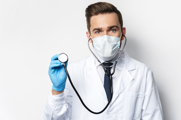 Zuversichtlicher Arzt mit dem Stethoskop mit Präventionsmaske und Latexhandschuhen