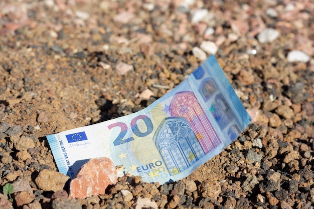 Zwanzig-Euro-Schein auf Bodengrund mit Stein auf der Oberseite Grundstücksinvestitionsimmobilien-Geldinvestorenkonzepte
