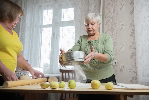 Zwei ältere Frau, die kleine Torten macht Sieben von Mehl Porträt