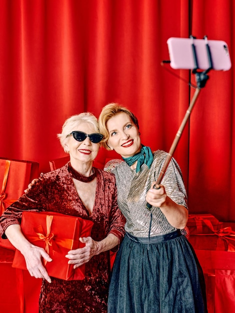 Zwei ältere Frauen auf der Party machen Selfie mit Handy auf Selfie-Stick. Party, Feier,