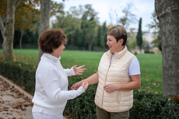 Zwei ältere Frauen draußen. Unterhaltung mit zwei älteren Frauen. Zwei alte Freunde, die im Park plaudern Lächelnde Frauen mittleren Alters, die sich im Freien unterhalten