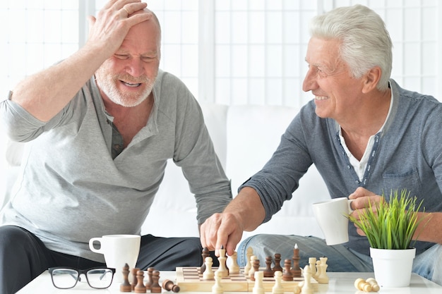 Zwei ältere Männer, die Spaß haben und zu Hause Schach spielen