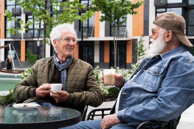 Zwei ältere Männer in der Stadt, die zusammen Kaffee trinken und sich unterhalten