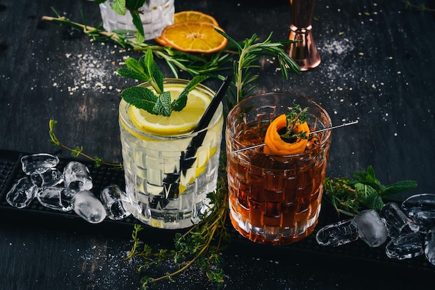 Zwei alkoholische Cocktail Gin und Tonic Negroni auf schwarzem Holzhintergrund