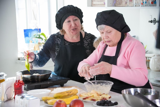 Zwei alte Frauen backen Pfannkuchen in der Küche