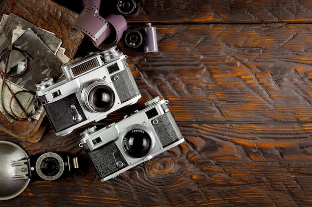 Foto zwei alte kameras auf einem holztisch mit lederriemen.