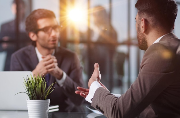 Zwei Angestellte in einem modernen Büro arbeiten an einem Tisch, Kollegen diskutieren und beraten sich