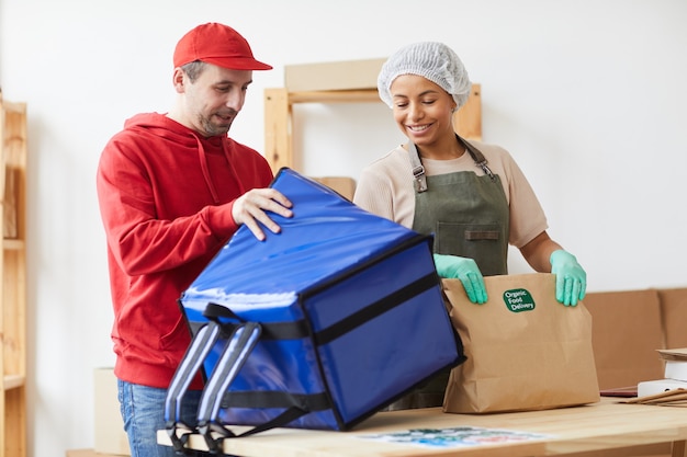 zwei Arbeiter lächeln beim Verpacken von Bestellungen beim Lebensmittellieferservice