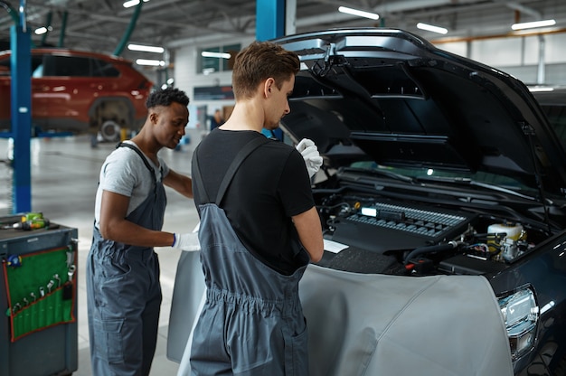 Zwei Arbeiter reparieren den Motor in einer mechanischen Werkstatt.