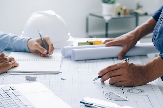 Zwei Architekten diskutieren ein Projekt und arbeiten an einer Blaupause auf der Baustelle im Büro