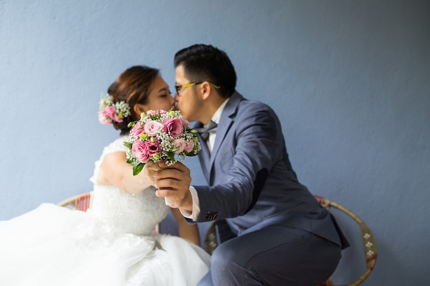 Zwei Asiaten küssen sich am Valentinstag hinter einem Blumenstrauß