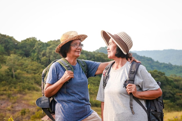 Zwei asiatische ältere Frauen beim Trekking Stehen auf einem hohen Berg mit Blick auf die wunderschöne Naturlandschaft Das Konzept des Naturtourismus im Rentenalter