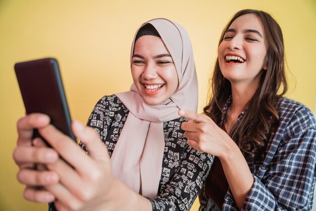 Zwei asiatische Frauen lachen glücklich während eines Videos mit einem Smartphone