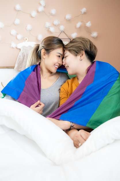 Zwei asiatische Frauen lgbtq lesbische homosexuelle lesbische Paare, die auf dem Bett liegen und zusammen schauen, lächeln und sich zu Hause entspannen Asiatische Frau LGBTQLGBTLGBTQ liebt auf weißem Bett und geht zusammen