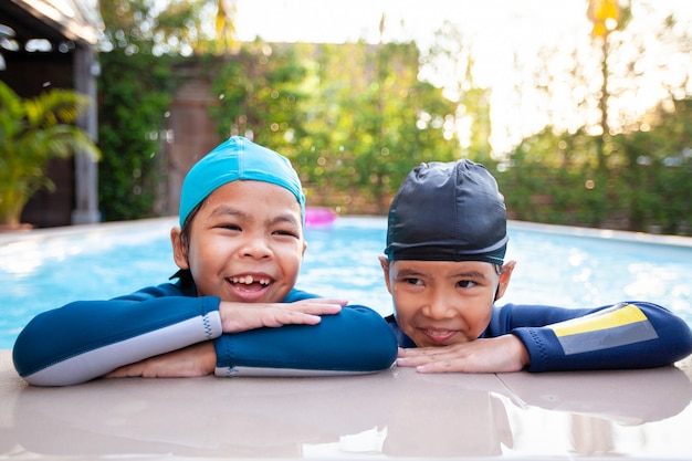 Zwei asiatische Kindermädchen im Schwimmbad und spielen zusammen Wasser mit Spaß