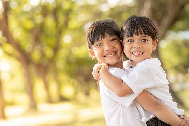 Zwei asiatische kleine Kindermädchen, die sich mit Liebe umarmen