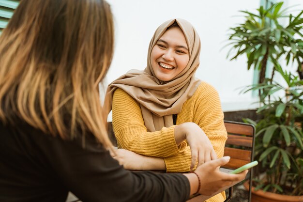 Zwei asiatische Mädchen plaudern und halten ein Handy