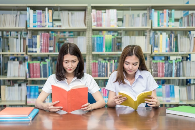 Zwei asiatische Studenten, die zusammen in der Bibliothek an der Universität studieren.