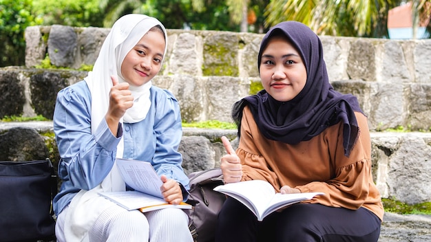 Zwei asiatische Studentinnen, die mit ok Geste diskutieren